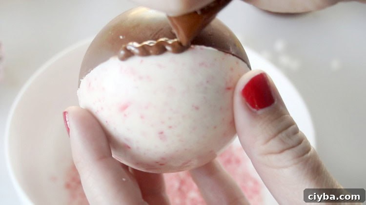 drizzling melted chocolate over seam of hot chocolate bomb