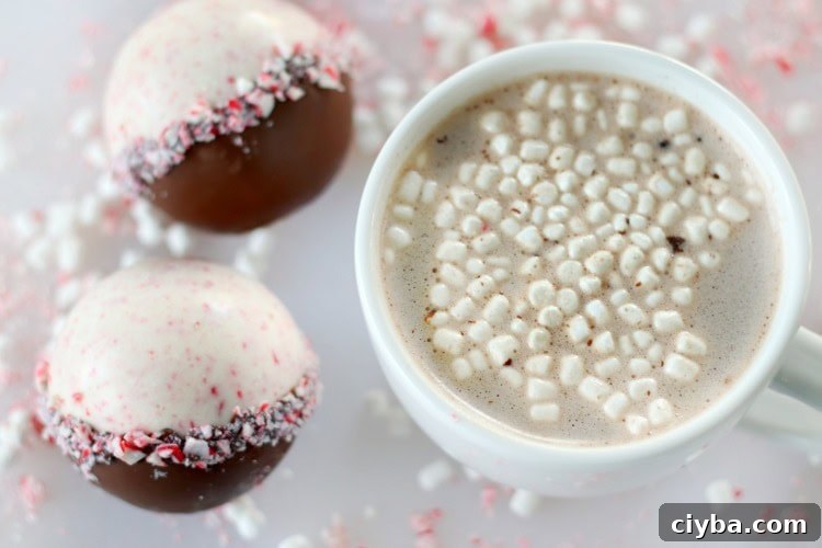 2 peppermint hot chocolate bombs next to white mug of hot chocolate
