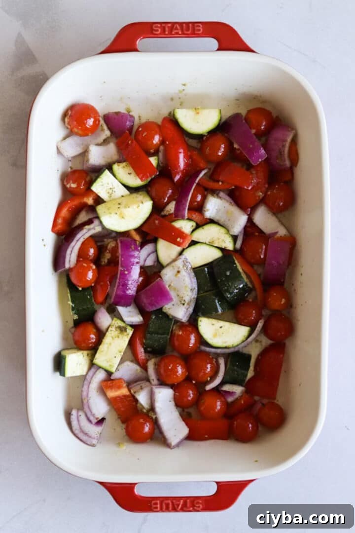Raw vegetables and a block of feta in a baking dish
