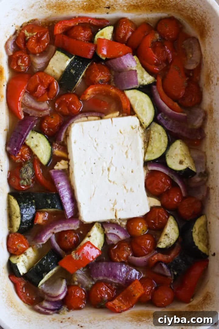 Roasted vegetables and large block of feta in a baking dish