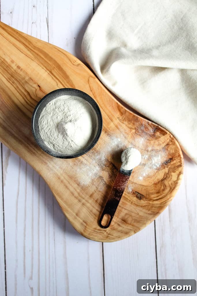 potato flour in a spoon sitting on a wooden cutting board.