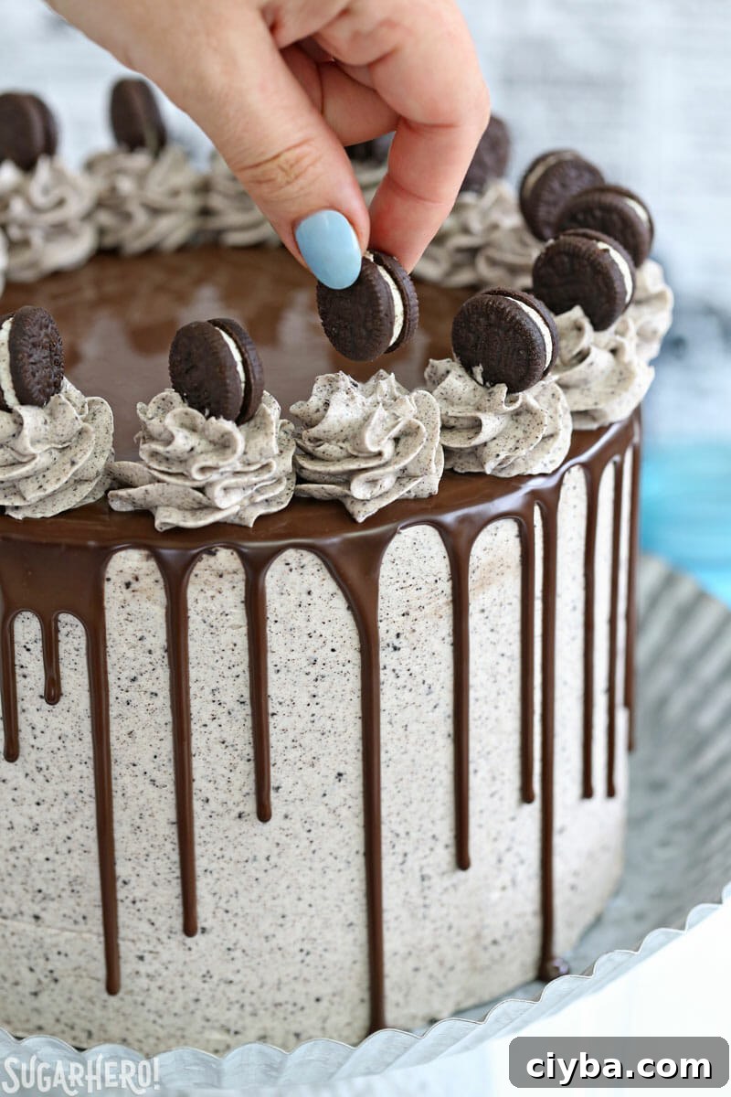 Cookies and Cream Cake - hand placing mini cookie on top of cake