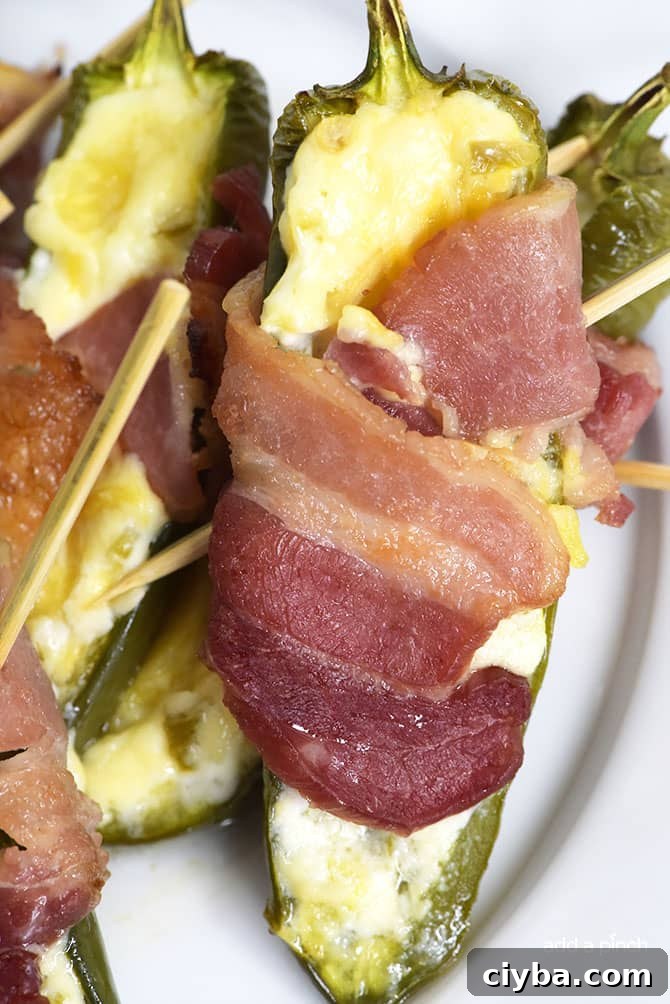 Pineapple Jalapeno Popper Recipe - Sweet and spicy, these jalapeno poppers are made with a pineapple cream cheese spread, wrapped with bacon and baked to perfection!