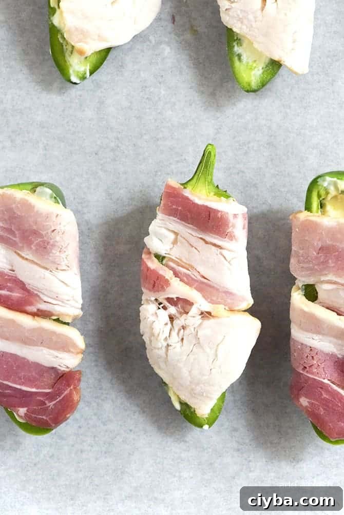 Pineapple Jalapeno Popper Recipe - Sweet and spicy, these jalapeno poppers are made with a pineapple cream cheese spread, wrapped with bacon and baked to perfection!