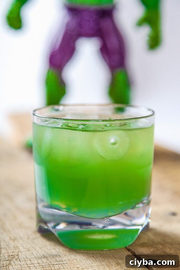 Incredible Hulk Cocktail: Classic Green Cognac Drink 10 a bright green cocktail on a wooden table.