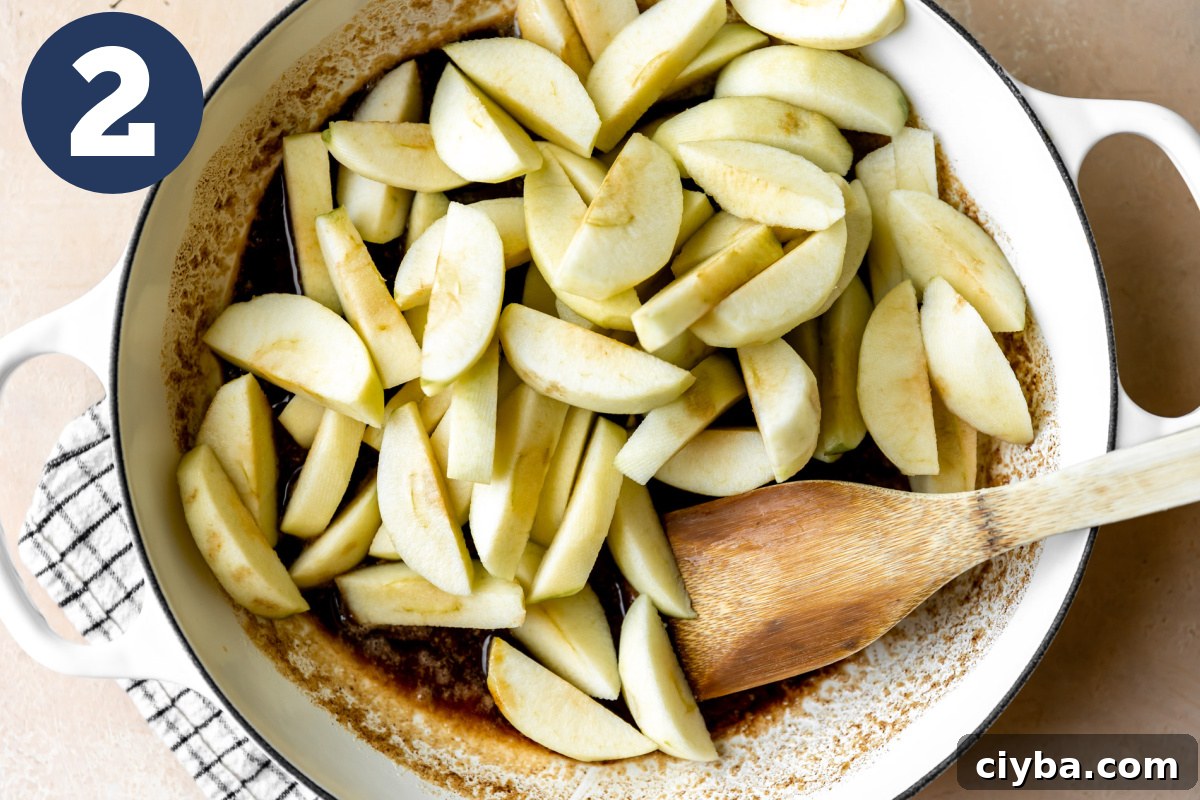 Cut apples added into a skillet with melted butter and spices.