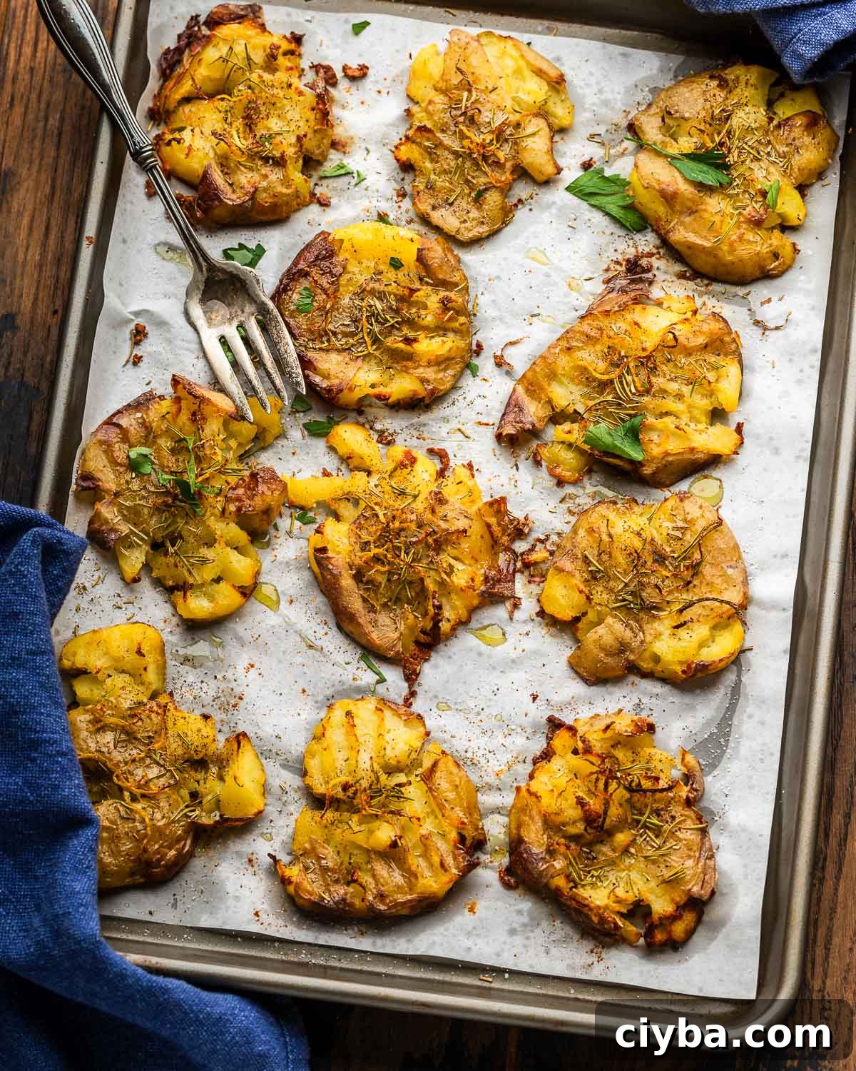 Baking sheet with rosemary lemon smashed potatoes and large fork.
