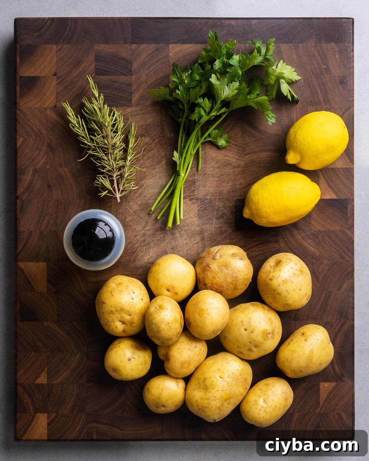 Ingredients shown: rosemary, parsley, lemons, olive oil, and Yukon Gold potatoes.