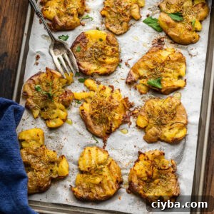 Baking sheet with rosemary lemon smashed potatoes and large fork.