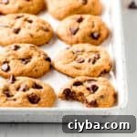 Gluten-free pumpkin chocolate chip cookies lined up on a white cookie sheet.