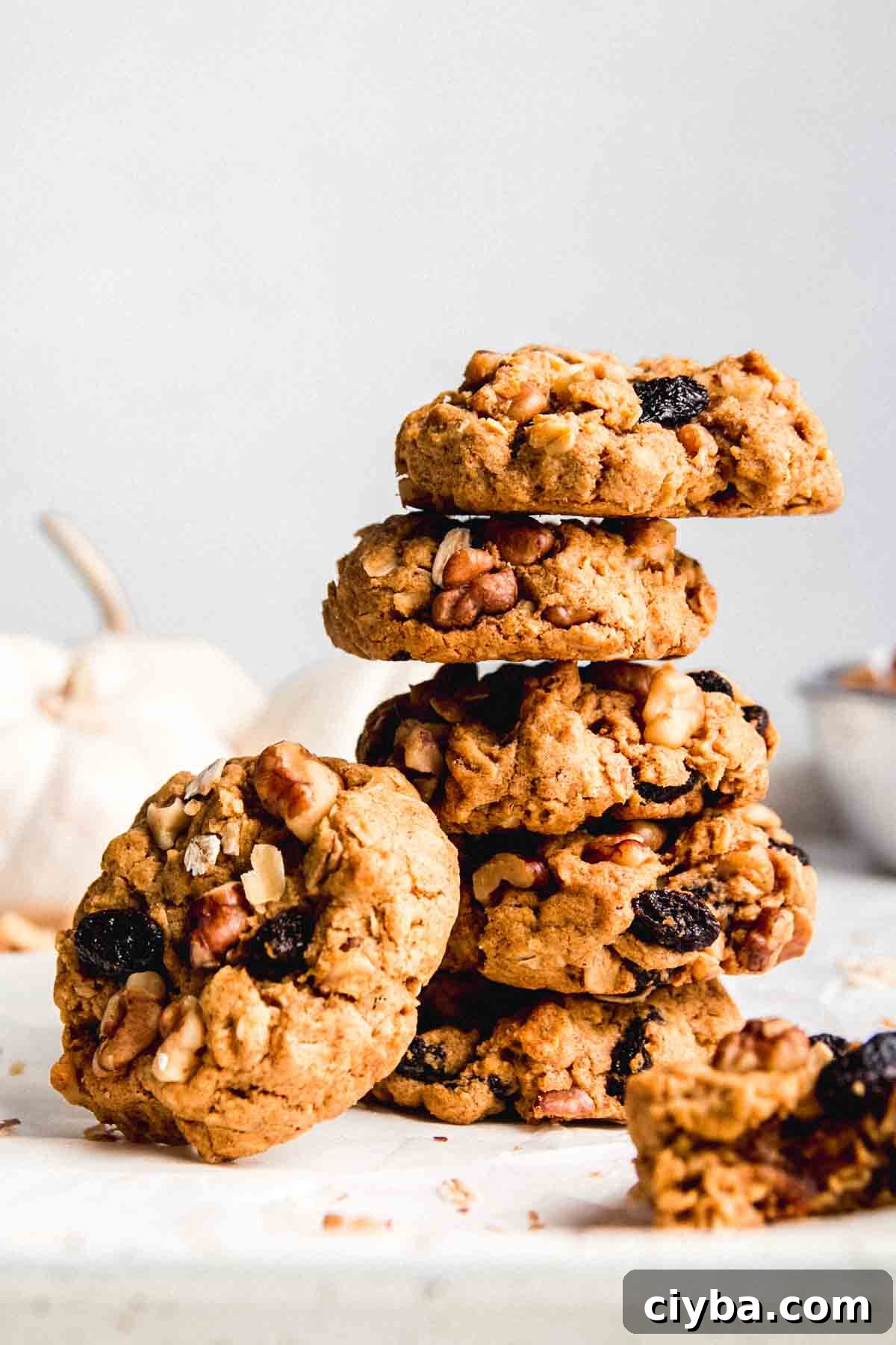 A stack of gluten free pumpkin oatmeal cookies with one cookie leaning on the side of the stack.
