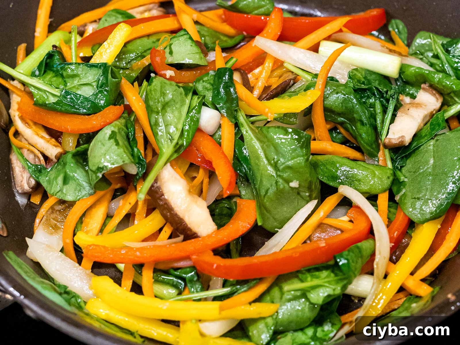 Authentic Japchae: Korean Glass Noodle Stir Fry Recipe 11 spinach, stir fried carrots, shiitake mushrooms, and bell peppers in a pan