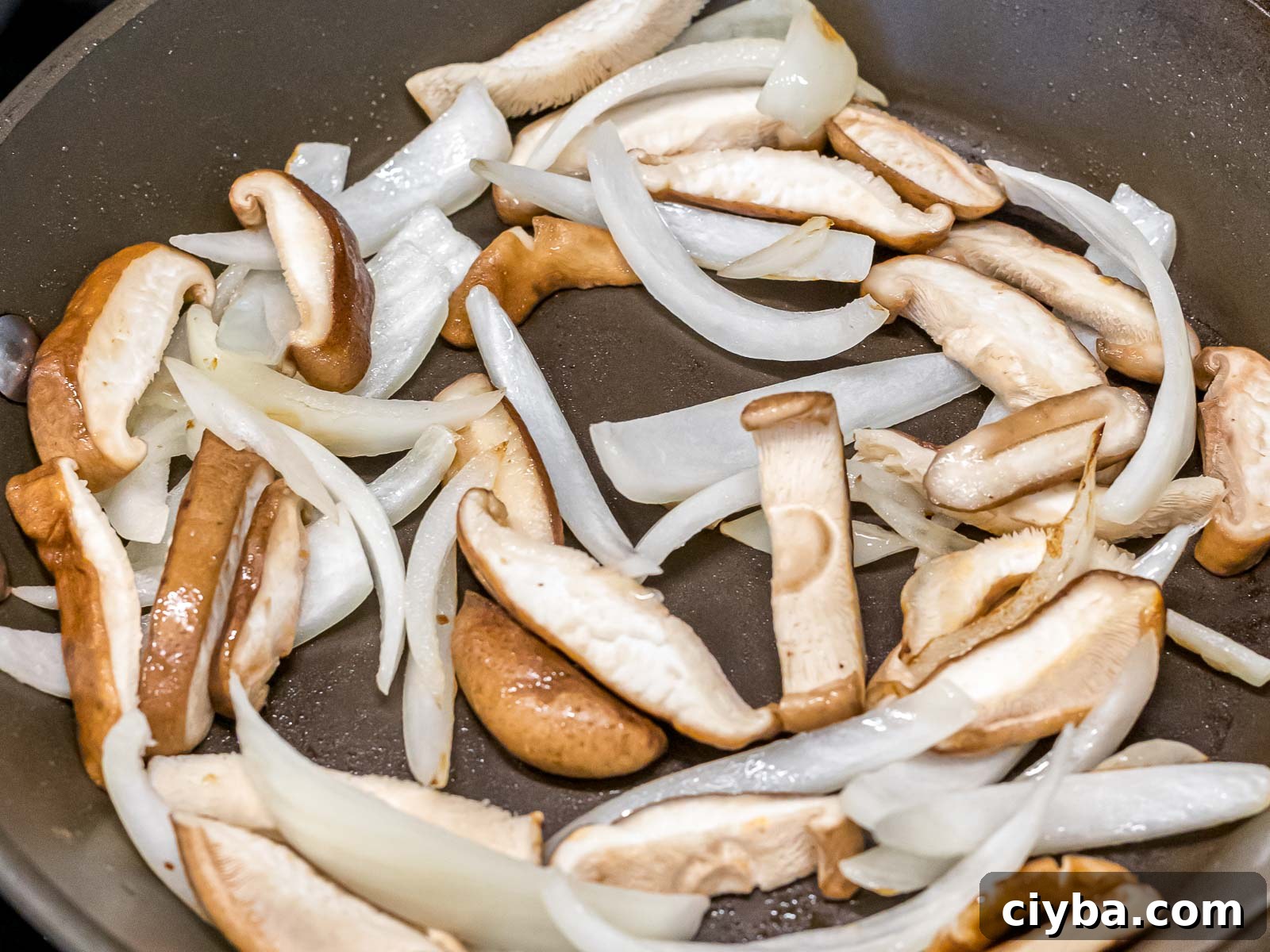 Authentic Japchae: Korean Glass Noodle Stir Fry Recipe 9 sliced shiitake mushrooms and white onions stir fried in a pan