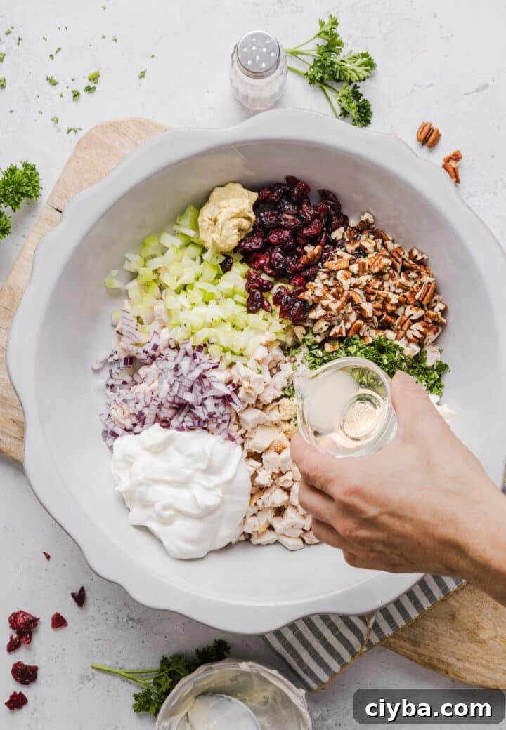 Cranberry Pecan Chicken Salad with Maple-Dijon Vinaigrette 4 Ingredients for cranberry chicken salad in a large white mixing bowl.