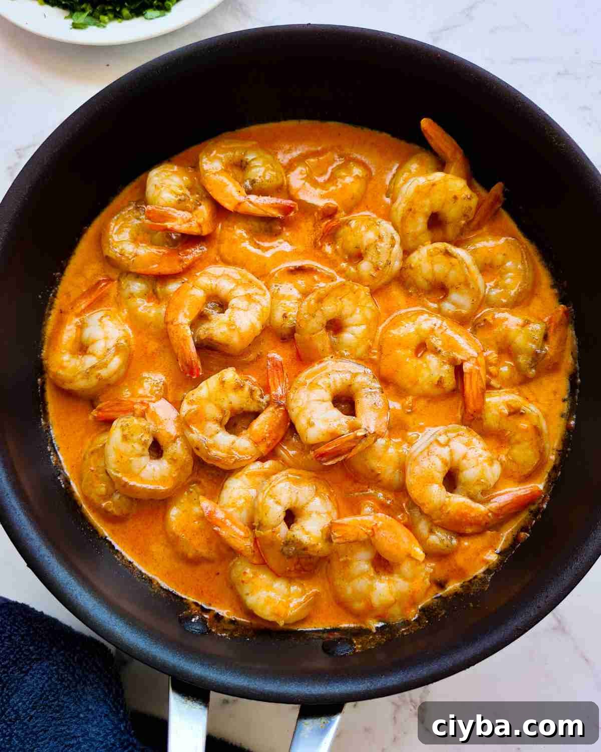 Glossy creamy garlic prawns (shrimp) in a frying pan