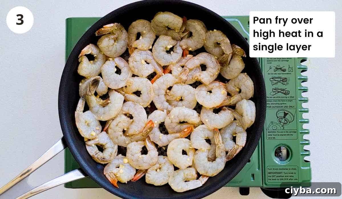 Shrimp (prawns) being sauteed in a frying pan with caption