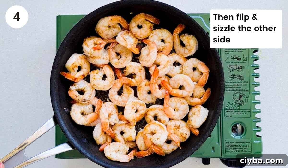 Shrimp (prawns) being sauteed in a frying pan that are cooked with caption