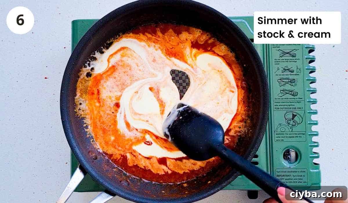 Creamy sauce being simmered in a frying pan with caption