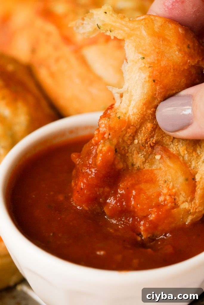 cheesy garlic knot being dipped in marinara sauce
