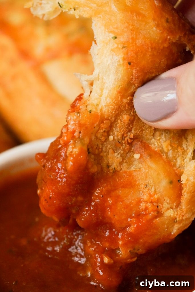 a crescent roll garlic knot dipped in marinara sauce