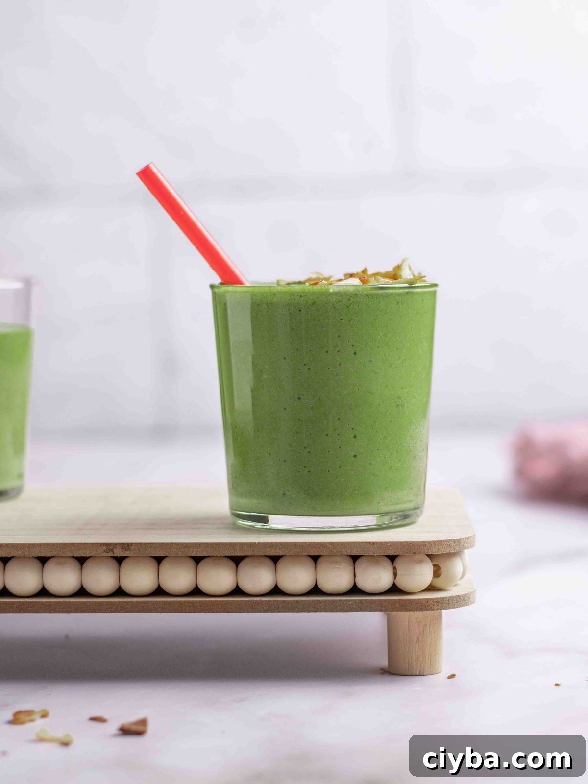 Banana spinach smoothie in a serving cup with straw.