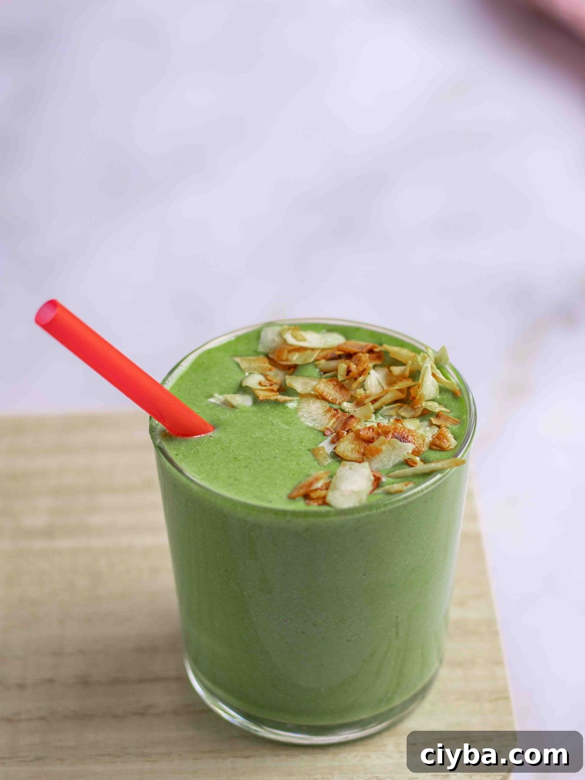 Smoothies on a wood stand garnished with toasted coconuts.