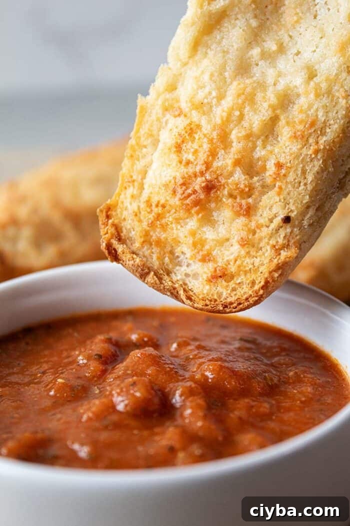 Keto Super Bowl Party Menu: Low-Carb Game Day Recipes 12 sideview of easiest low carb garlic bread being dipped into white bowl with marinara dipping sauce