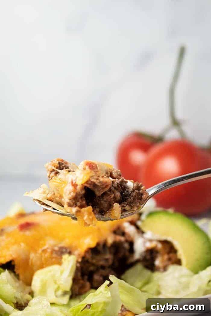 Keto Super Bowl Party Menu: Low-Carb Game Day Recipes 19 spoon full of beef held up in front of keto taco casserole with lettuce and avocado