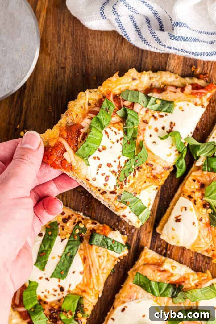 Keto Super Bowl Party Menu: Low-Carb Game Day Recipes 24 hand reaching out to grab slice of keto chicken crust pizza off cutting board