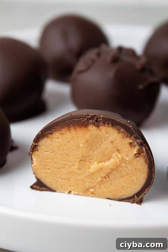 Keto Super Bowl Party Menu: Low-Carb Game Day Recipes 44 sideview of keto peanut butter balls on a white serving dish and one of them is cut in half revealing the peanut butter interior