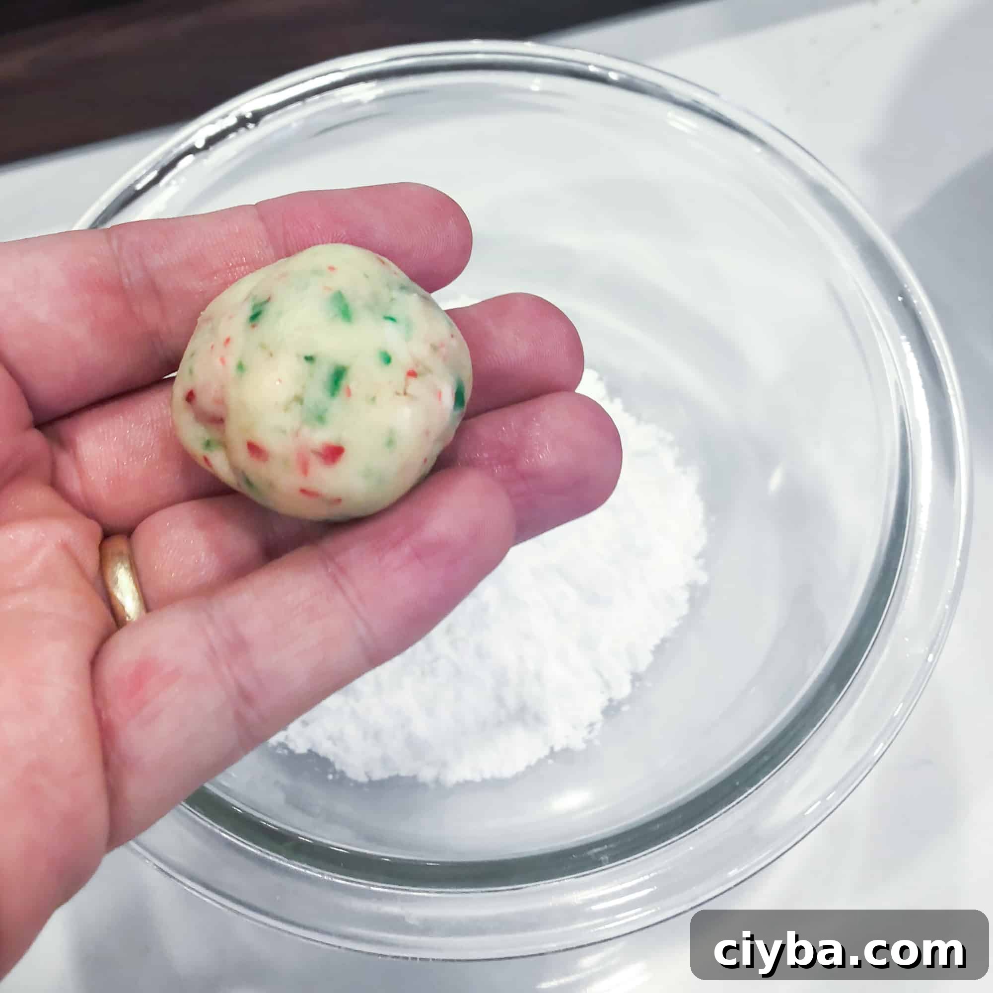 Roll the cookie dough into a ball and then toss in icing sugar.