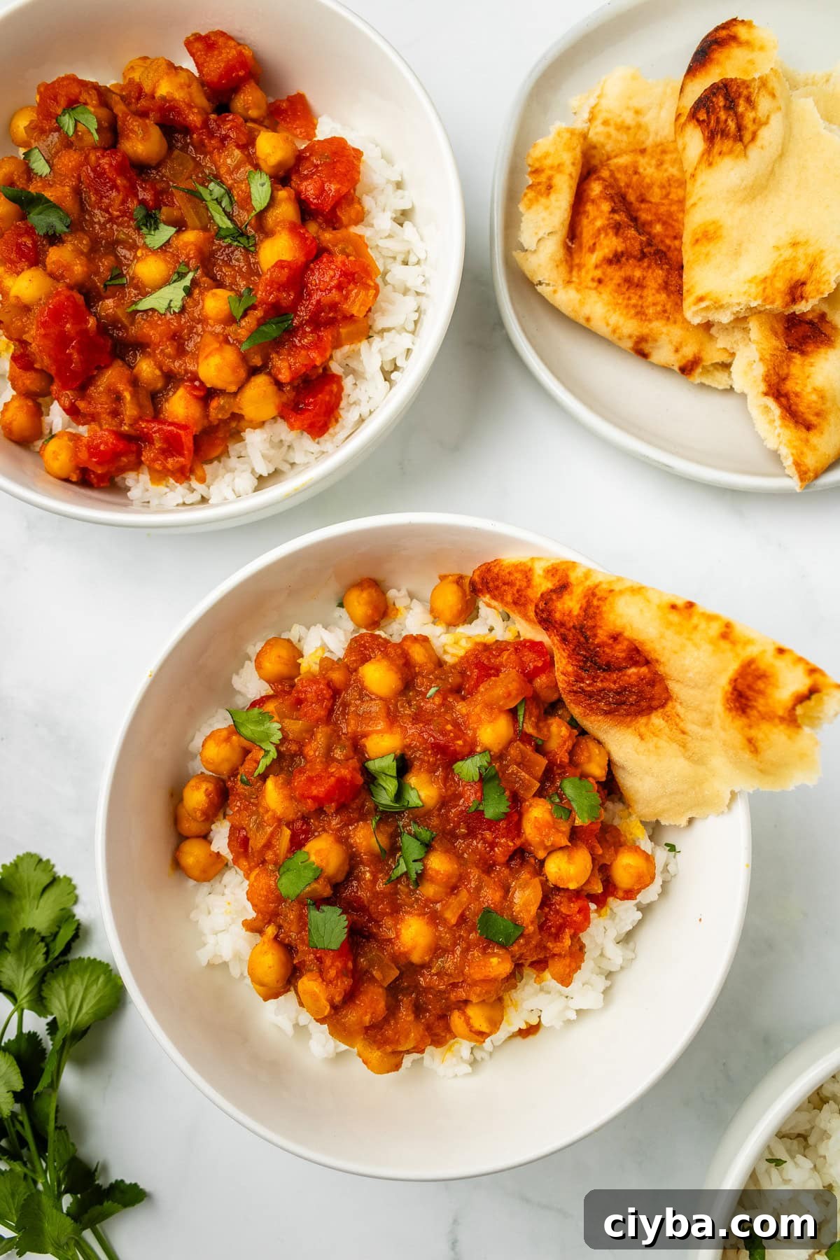 An overhead image of chana masala in a bowl with naan bread on the side.