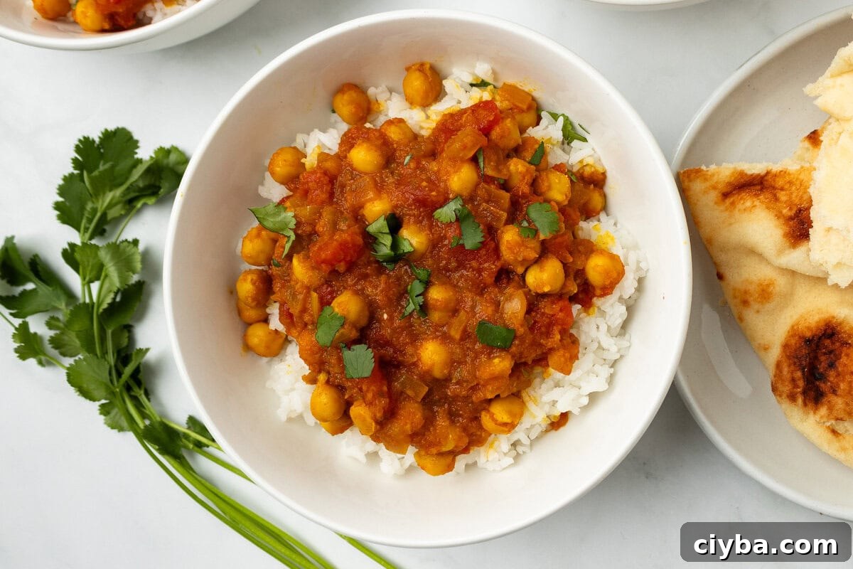 An overhead image of chana masala in a bowl with naan bread on the side.