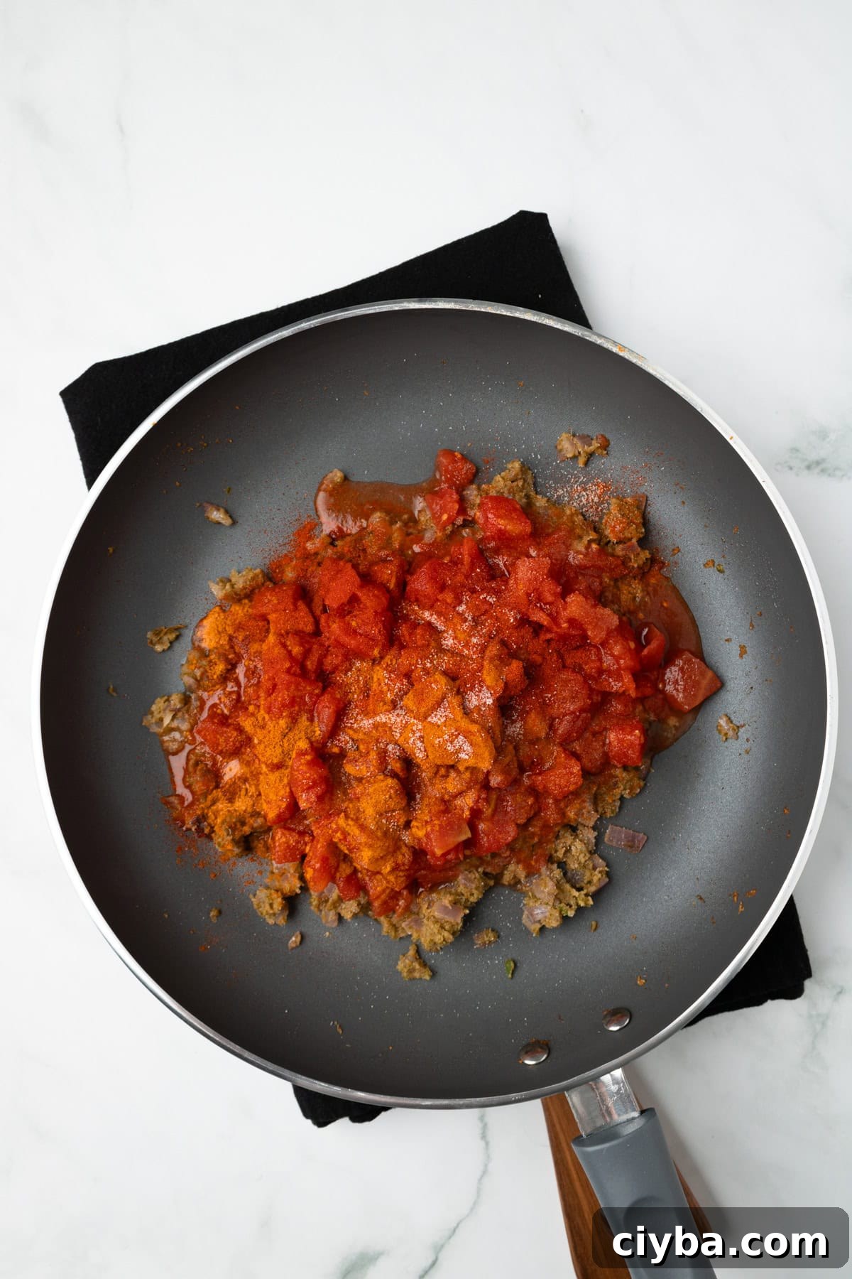 An overhead image of adding the diced tomatoes.
