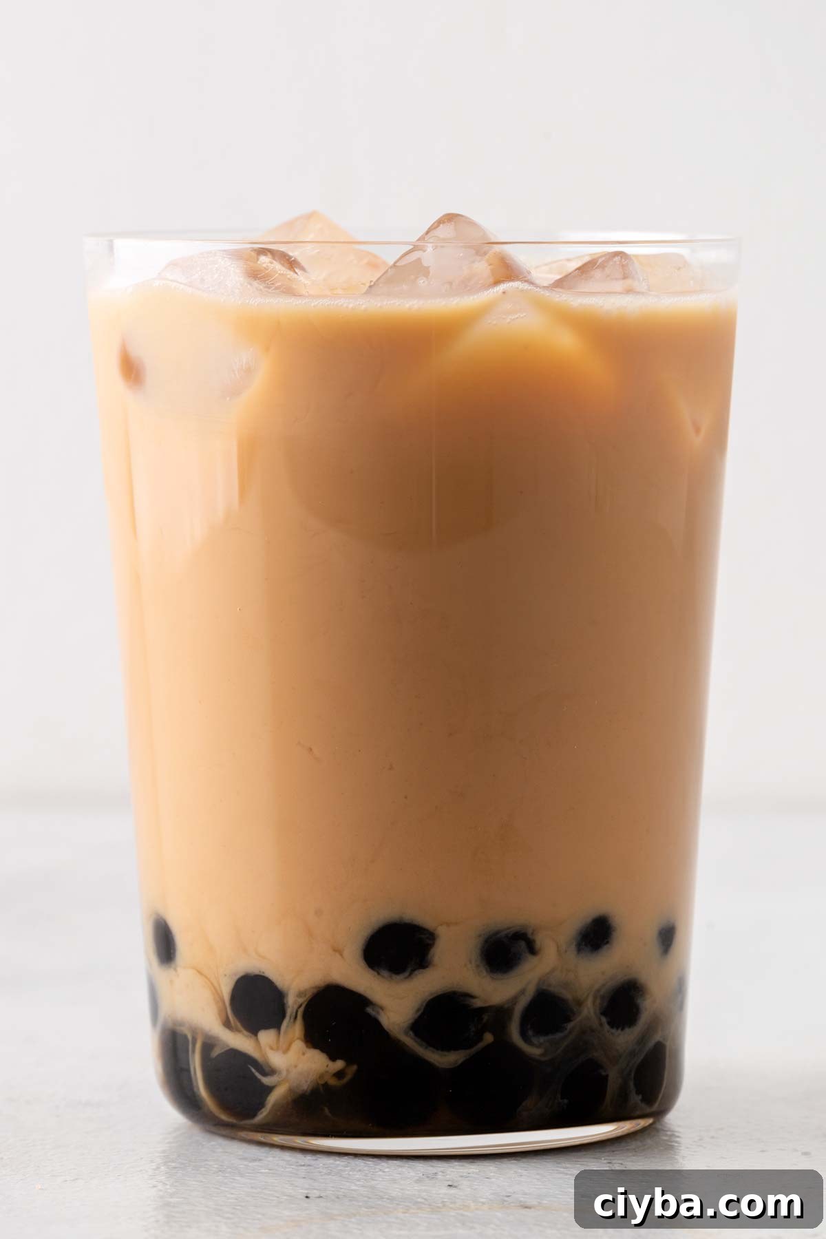 Finished Hong Kong Milk Tea (Hong Kong Bubble Tea) in a clear glass with boba at the bottom and ice on top.