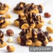 Snickers keto fat bombs are low-carb candy clusters on white marble background with scattered peanuts.