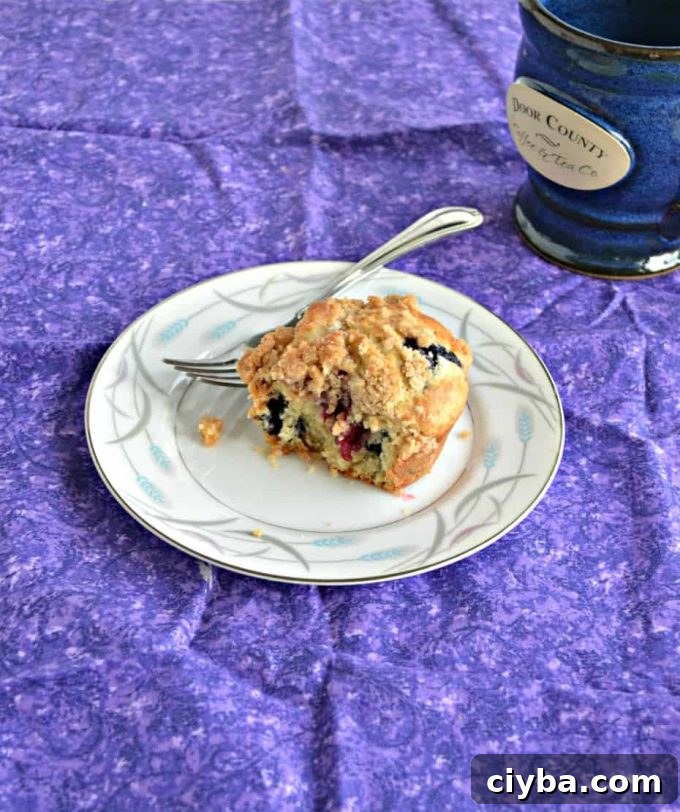 A berry muffin made with sourdough discard sitting on a plate with a fork.