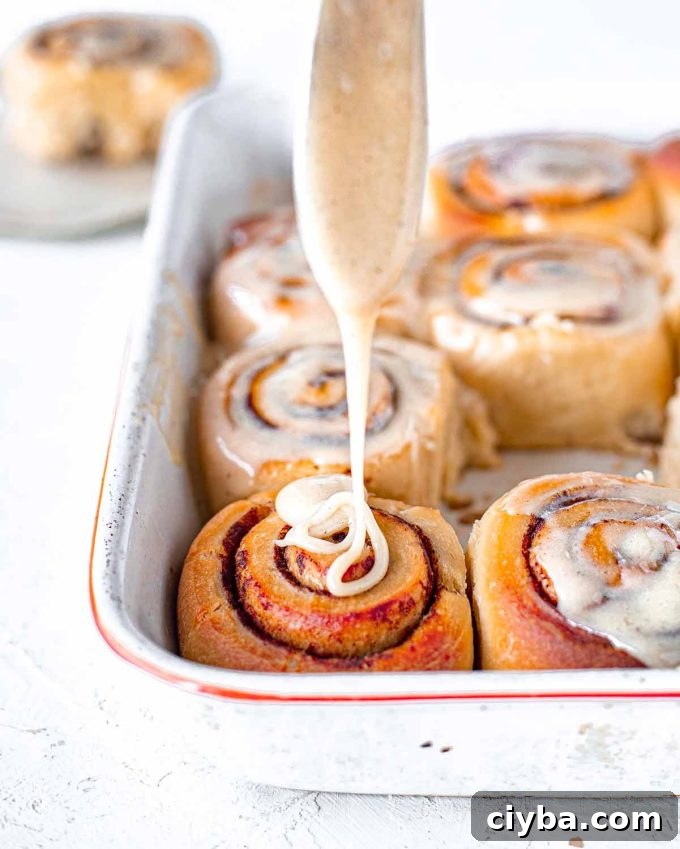 Drizzling a glaze onto sourdough cinnamon rolls.