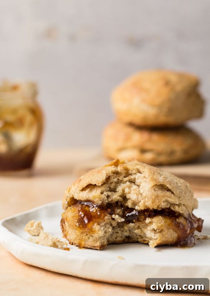 A sourdough biscuit on a surface with jam spilling out of it. 