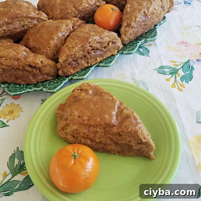 Pumpkin spice sourdough scone sitting on a green plate with a clementine.