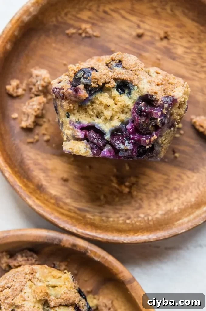A blueberry sourdough muffin with a bite taken from it lying on a surface.