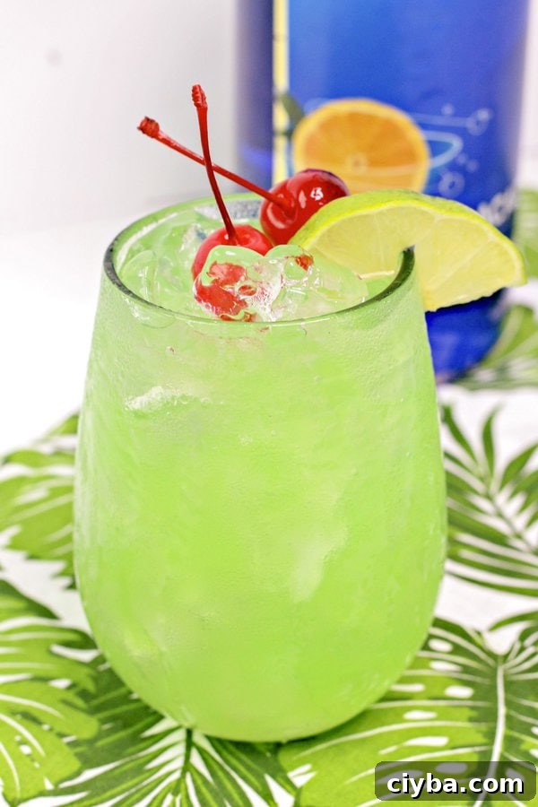 Mermaid Cocktail Recipe: Tropical Blue Drink 2 a bright green mermaid drink garnished with maraschino cherries and lime.