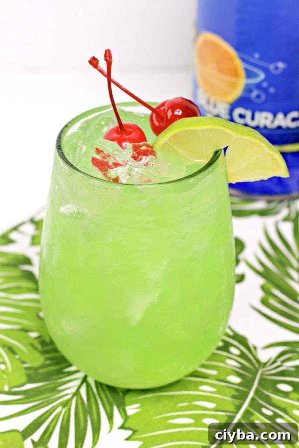 Mermaid Cocktail Recipe: Tropical Blue Drink 4 mermaid water cocktail on a green plant placement with blue curacao in the background.