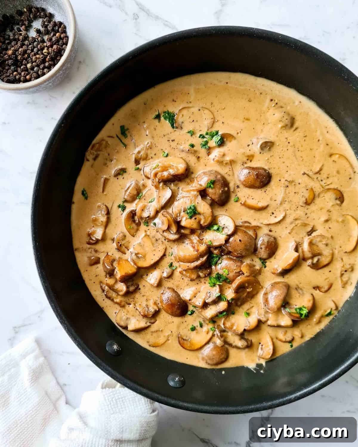 Overhead, zoomed out view of mushrooms in creamy sauce in a black pan, ready to serve