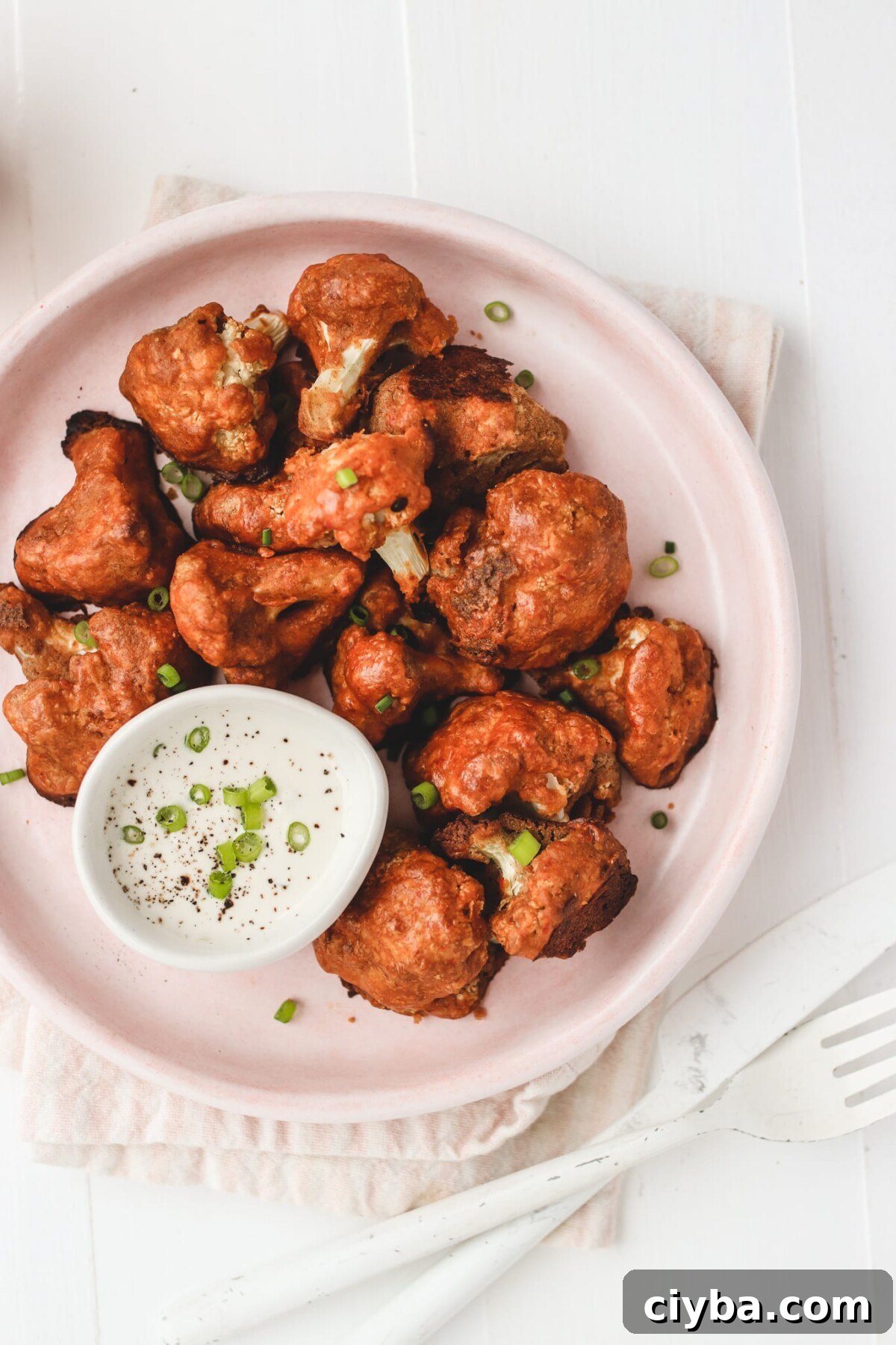 Crispy Vegan Buffalo Cauliflower Wings Recipe 5 cauliflower buffalo wings on a pink tray with dipping sauce