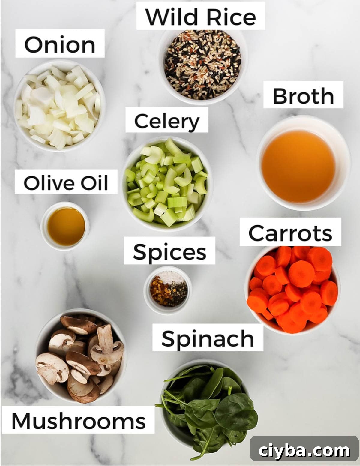 Small white bowls filled with ingredients that are individually labeled including: wild rice, onion, broth, celery, olive oil, spices, carrots, spinach, mushrooms.