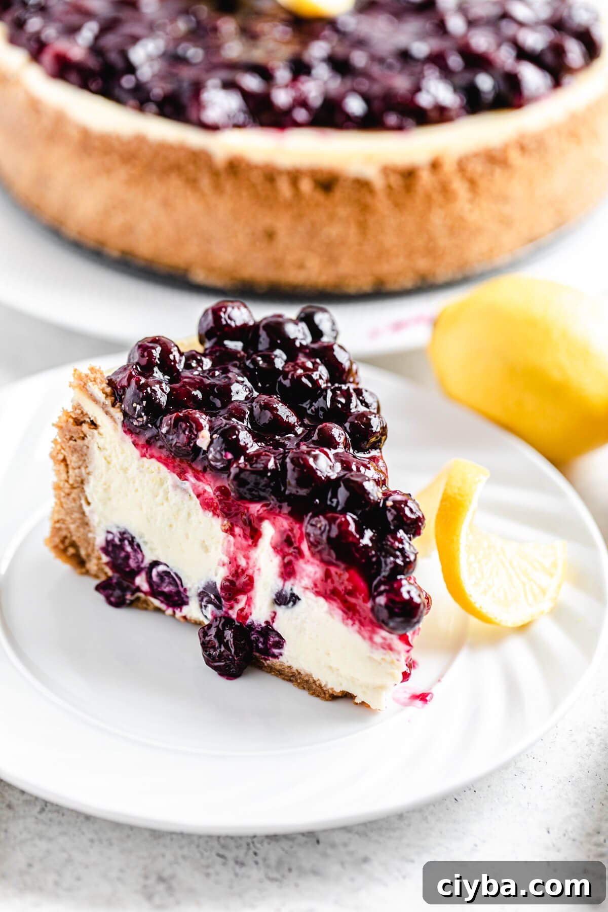 slice of cheesecake on a white plate with whole cheesecake in the background