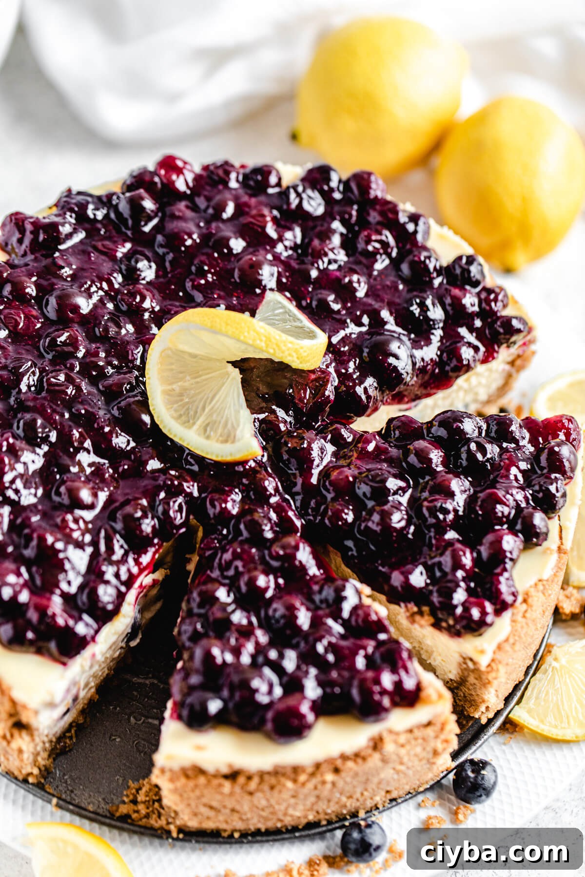 close up of sliced cheesecake with two lemons behind it