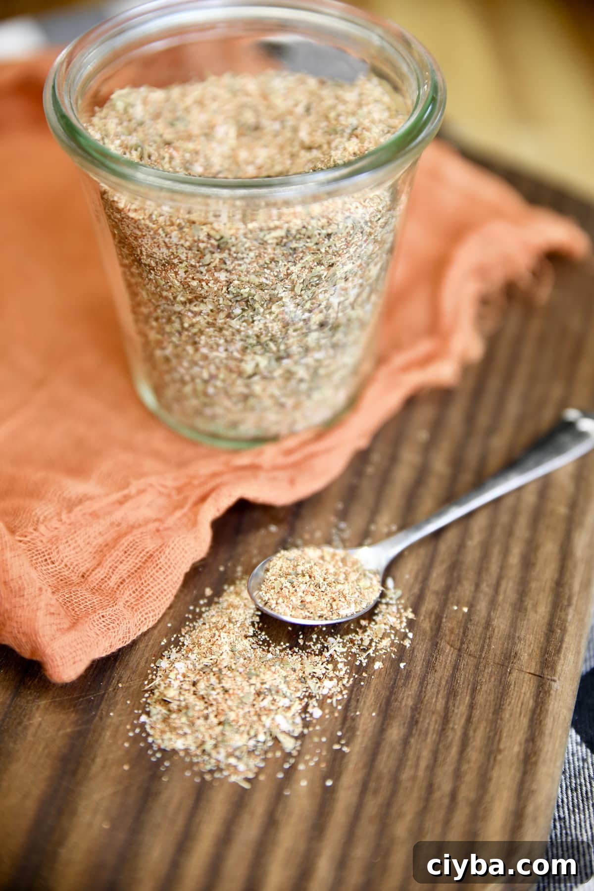 Jar of spice rub, spoonful spilled onto board.