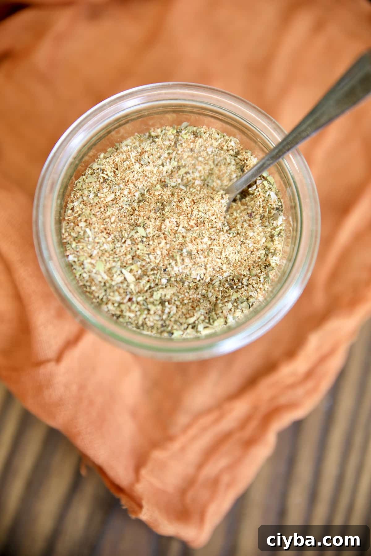 Italian Rub in a jar with a spoon on an orange cloth.